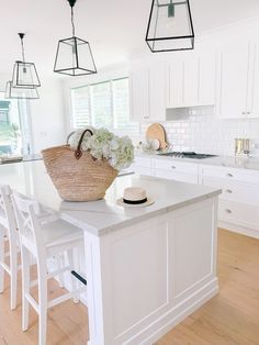 a kitchen with white cabinets and an island that has a basket on top of it