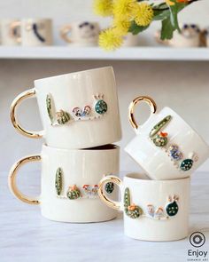 four mugs with cactus designs on them are stacked next to each other in front of yellow flowers