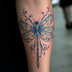 a woman's leg with a dragonfly tattoo on it and an arrow in the center