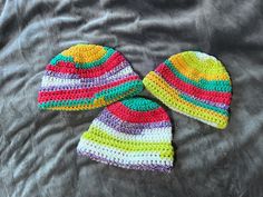 two crocheted hats laying on top of a bed