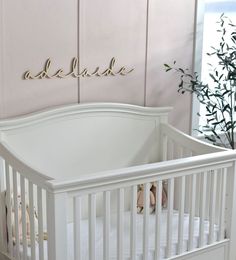 a white crib in front of a pink wall with the name amelie on it