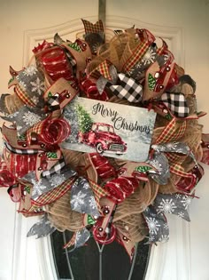 a christmas wreath with a red truck and plaid ribbon hanging on the front entrance door