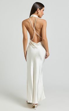 the back of a woman wearing a long white dress with straps on her neck and an open