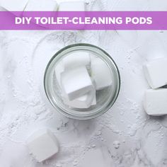 a jar filled with lots of white cubes on top of a counter next to a pile of toilet paper