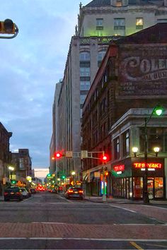 a city street filled with lots of traffic and tall buildings at dusk, during the day