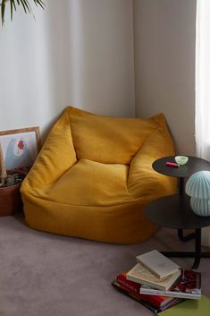 a yellow bean bag chair sitting next to a table with books on top of it