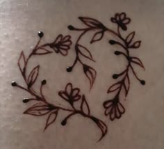 a woman's back with a tattoo design on her stomach that has flowers and leaves drawn on it