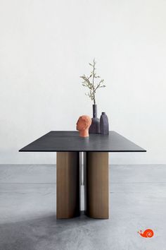 a black table with two vases and a plant on it