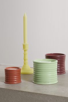 three different colored candle holders sitting on top of a cement counter next to each other