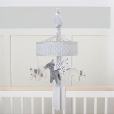 a baby crib with an elephant, giraffe and zebra mobile on it