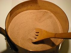 a wooden spoon in a pot filled with sand