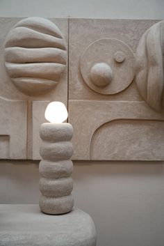 a white lamp sitting on top of a table next to a wall mounted art piece