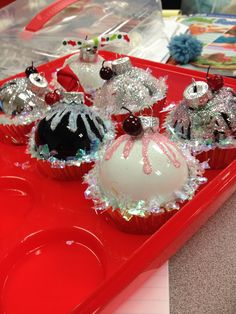 some cupcakes are on a red tray with white frosting and silver decorations