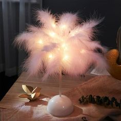 a table topped with a white vase filled with feathers