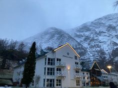 a large white building sitting in front of a snow covered mountain