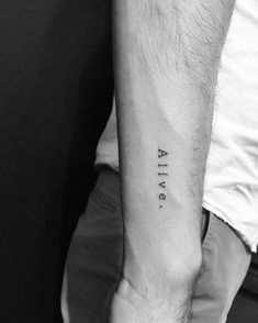 a man's arm with the word alive tattooed on his left forearm, in black ink