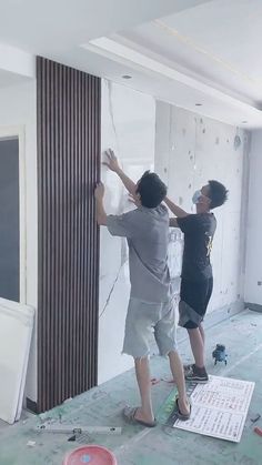 two men are painting the walls in an unfinished room