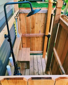 an outdoor shower with wooden fence and green grass in the back yard, next to a garden hose