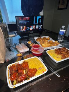 several trays of food on a table with a television in the background