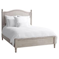 a bed with white linens and pillows on it's headboard is shown