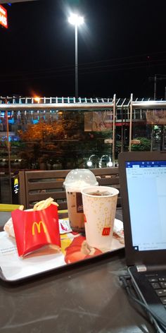 a laptop computer sitting on top of a table next to a tray filled with food