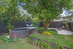 an outdoor hot tub in the middle of a yard with trees and plants around it