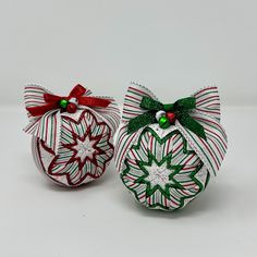 two christmas ornaments with bows on them sitting next to each other, one green and one red