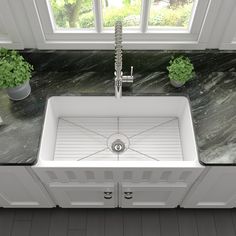 a white sink sitting on top of a counter next to a green potted plant