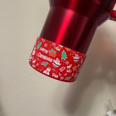 a red coffee mug with christmas decorations on it and a cup holder attached to the handle