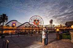 a man and woman standing in front of a ferris wheel