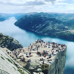 a group of people standing on top of a cliff next to a body of water