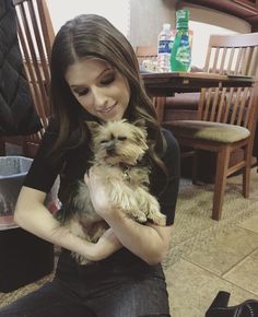 a woman sitting on the floor holding a small dog