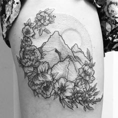 a woman's thigh with flowers and mountains in the background on her right side