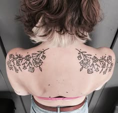 the back of a woman's shoulder with tattoos on it and flowers all over her body