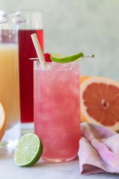 two glasses filled with drinks next to sliced oranges and grapefruit