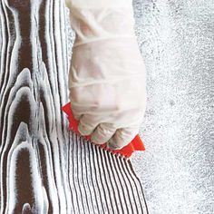 a person's hand holding a brush on top of a wooden floor covered in snow