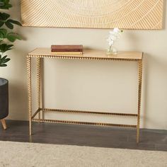 a gold console table in front of a painting and potted plant on the floor