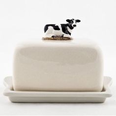 a small black and white cow figurine sitting on top of a cake plate