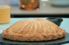 a baked pastry sitting on top of a black plate next to a stack of yellow plates