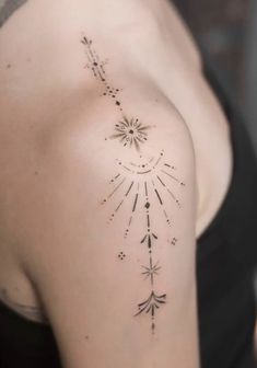 the back of a woman's shoulder with an arrow and stars tattoo on it