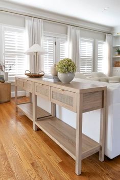 a white couch sitting next to a wooden table in a living room filled with furniture