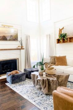 a living room filled with furniture and a fire place next to a window on top of a hard wood floor