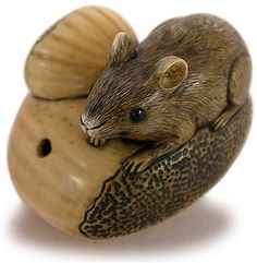 a figurine of a mouse sitting on top of an acorn or shell