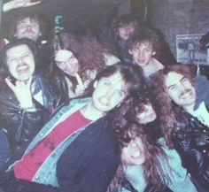 a group of people standing next to each other in front of a brick wall with their mouths open