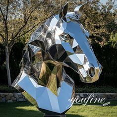 a large metal horse head sitting on top of a lush green field