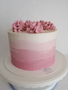 a cake with pink frosting and flowers on top is sitting on a platter