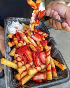 a person is cutting strawberries into small pieces on a tray with other foods in it