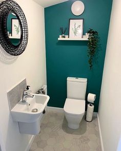 a white toilet sitting next to a sink in a bathroom under a mirror and a potted plant