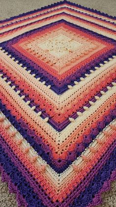 a crocheted blanket is laying on the floor