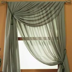 a window with sheer curtains hanging from it's side